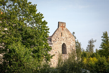 Ancient Stone Church Ruins with Cross Surrounded by Green Trees on a Sunny Day
