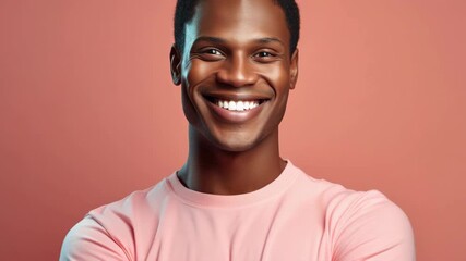 Young athletic man in pink shirt smiling towards camera with hands on hips.