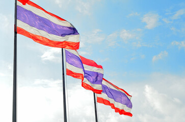 The Thai flag has been waving in the wind against a blue sky, its red, white, and blue colors a patriotic symbol of freedom.
