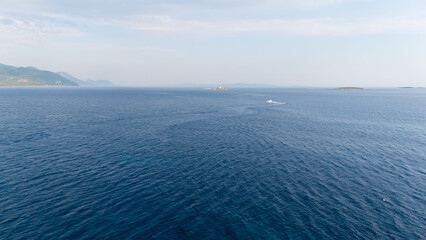 The ocean is calm and clear, with a few boats in the distance © Nikname