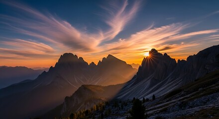 Naklejka premium Dramatic mountain peaks silhouette against a vibrant sunset, showcasing a breathtaking vista of golden light and swirling clouds.