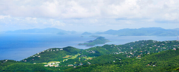 Panoramic view of St. Thomas, US Virgin Islands. Lush green hills, scattered villas and the vast Caribbean Sea with distant islands under cloudy tropical skies