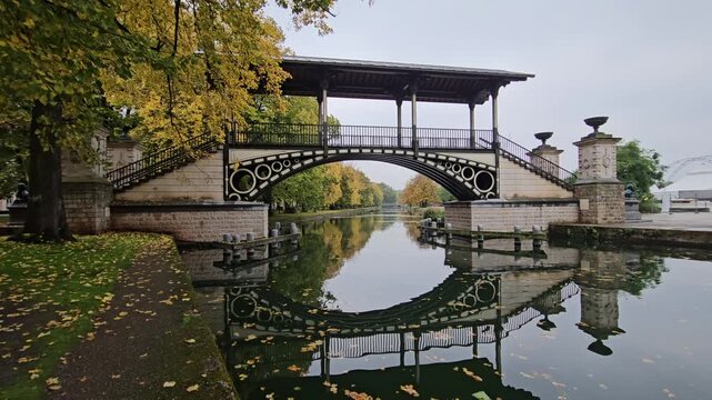 Historic Pont Napoleon bridge crossing the Moyenne - De&ucirc;le river with autumn trees in Lille, France