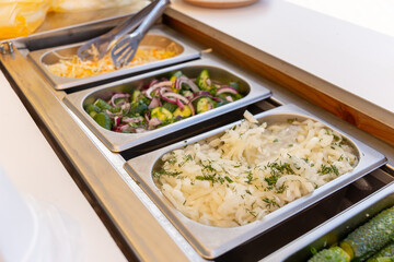 Fresh vegetable salads, pickled cucumbers and tomatoes, and other snacks on a buffet table.