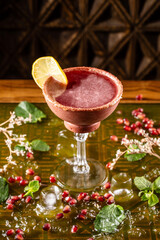 Red cocktail with lemon slice and sugar rim.