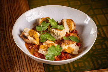 Bread with vegetable stew and herbs in a bowl.