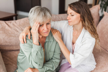 Fototapeta premium Grown up daughter soothe aged mother holds her hand feel empathy give her moral support, sad elderly woman at home