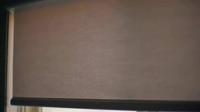 Demonstration of the operation of a roller blind in a modern living room (closing and partially opening the curtain)