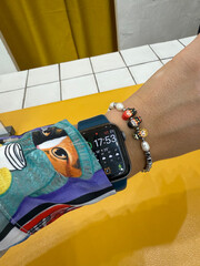 Naklejka premium Russia, Astrakhan, 2025-08-15 - A stylish wrist adorned with a smartwatch and a charming beaded bracelet featuring Harry Potter characters.