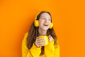 Fototapeta premium Cheerful young woman girl in yellow hoody posing isolated on yellow wall background