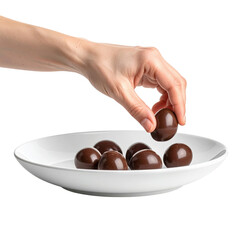 Hand picking a round chocolate candy from a white plate full of candies isolated on transparent background. PNG die-cut for advertising