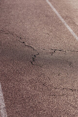 Closeup of rubber surface of stadium running track - old cracks on athlete path