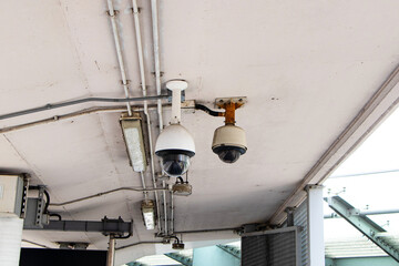 Old Closed-circuit camera CCTV hanging from ceiling on walkway on bridge with electrical conduit. Safety protection. Record events such as traffic accidents. Also prevent thief. Modern technology.