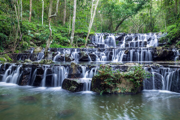 Samlan Waterfall, tier 1, tropical waterfall cascading over layered black rocks in lush rainforest of Thailand.
