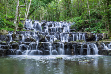 Samlan Waterfall, tier 1, lush tropical waterfall cascading over black rocks in forest stream in Thailand