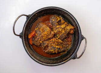 Close-up shot of a delicious and spicy homemade tilapia fish curry, served hot in a traditional Karahi or Kadai dish. A perfect representation of Asian cuisine. Top view.