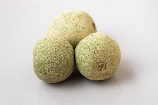 Close-up of three raw Wood apples (Limonia acidissima) on a clean white background. This exotic fruit is also known as Bael, Monkey Fruit, Kothbel, Kodbel.