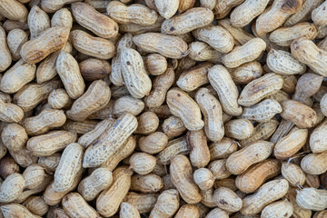 Close-up of a heap of unpeeled peanuts in their shells, showcasing their natural, detailed texture and pattern, ideal for a food background.