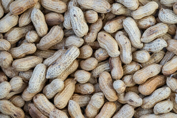 Close-up texture background of a heap of unpeeled peanuts in their shells. The natural patterns and textures of the peanut shells are highlighted in this detailed view.