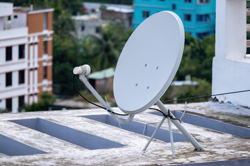 Close-up of a satellite antenna dish on the roof of a residential house in Bangladesh, highlighting the technology used for television access.