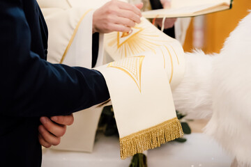 Close-up of priest’s stole placed over couple’s hands during wedding vow exchange ceremony in...