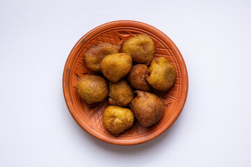Top view of delicious, soft, and spongy taler pitha (palm fritters), a traditional sweet Bangladeshi snack, served on a rustic clay plate.