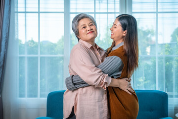Loving granddaughter hugging senior grandmother at home with happy smiles