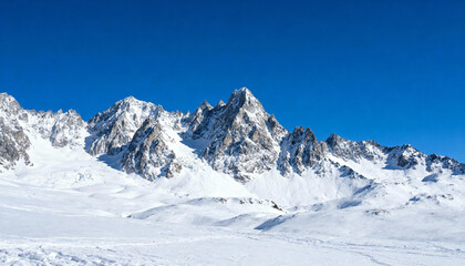 Majestic snowy mountain range on a clear sunny winter day. Alpine landscape with pristine snow peaks against a deep blue sky. Concept for adventure, travel, and freedom.