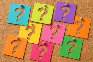 Vibrant, colorful question marks cut from paper squares are neatly pinned onto a textured cork board, symbolizing inquiry, problem-solving, and the exciting quest for knowledge or new ideas