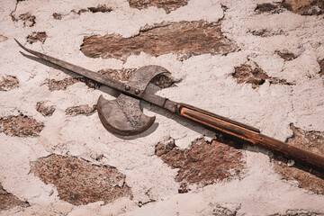 Close up of an ancient halberd resting on a damaged plastered wall, showcasing its age and historical significance