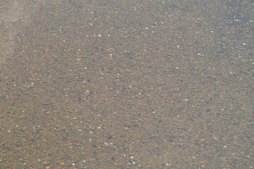 Background texture of gravel at the bottom of a clear and shallow river. Mountain river during the dry season