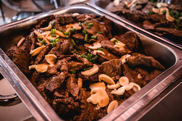 meat on a buffet table, roast meat, Brazilian party food, pan meat in sauce with mushrooms