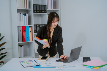 Young asian businesswoman smiling and working on digital tablet at office desk