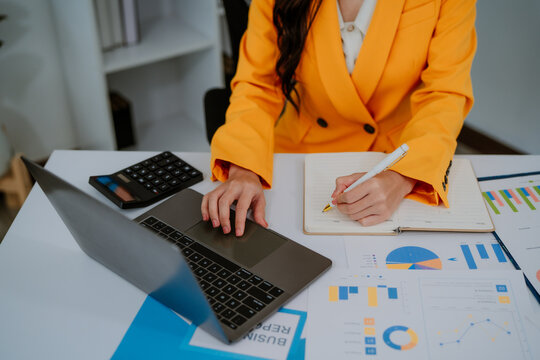 Business woman using tablet and laptop for doing math finance on an office desk, tax, report