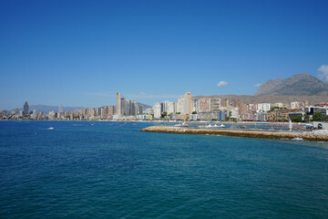 Fototapeta premium Sunny summer day in Benidorm, Spain showcasing the picturesque coastline with high rise hotels and cityscape views of the mountains