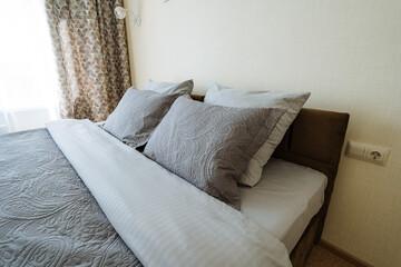 In a cozy bedroom, a neatly arranged bed is adorned with a fluffy white comforter and soft, inviting pillows, creating a warm atmosphere for relaxation and peaceful rest