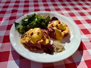 Gourmet beef sandwich with melted cheese and salad on checkered tablecloth