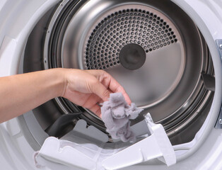 close up female hand taking lint out from dirty air filter of dryer machine after drying. cleaning...