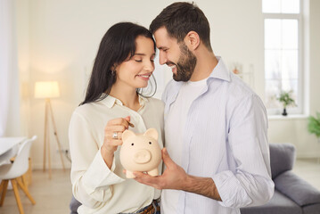 Savings for future, dream or new home. Young couple with piggy bank in their hands radiate...