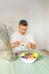 Caucasian Man in His 30s Eating Muesli at a Dining Table During Morning Routine.
