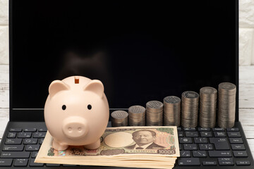 ノートパソコンと豚の貯金箱と一万円札