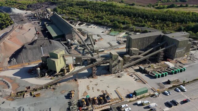 Aerial drone view of huge quarry mining operational facility, extracting rare earth minerals, heavy plant machinery and industrial conveyor belts in Coalville England UK sunny 