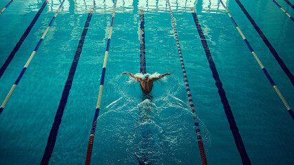 Professional swimmer in butterfly stroke captured mid-motion with inspiring power. Concept of motivational posters, sports journalism, fitness wellness promotion, and competitive advertising.