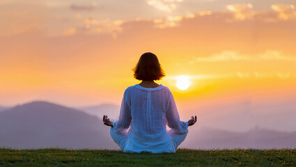 Woman meditating at sunset with mountains in the background promotes mindfulness and inner peace