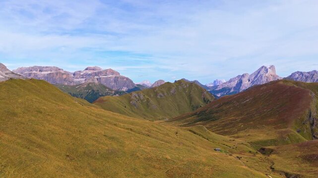 Veduta aerea mozzafiato delle Dolomiti con valli verdi, sentieri alpini e imponenti montagne rocciose sotto un cielo limpido. Un paesaggio naturale spettacolare che rappresenta la bellezza delle Alpi