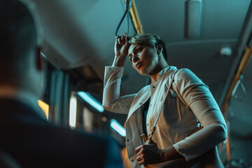 Woman looking exhausted after work standing on a bus