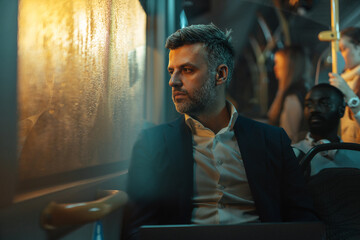 Man sittiing next to the window on a bus at night