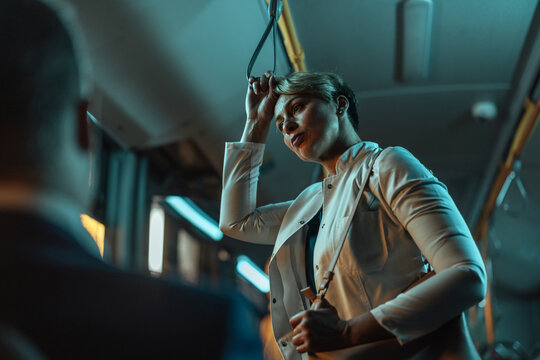 Woman looking exhausted after work standing on a bus - Powered by Adobe