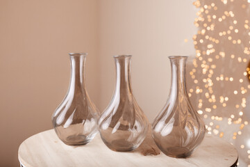 Glass vases on table with festive lights background