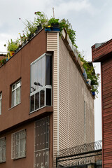Modern architectural structure featuring a unique corner design with lush greenery on the rooftop, showcasing urban innovation and sustainable living in contemporary city environments